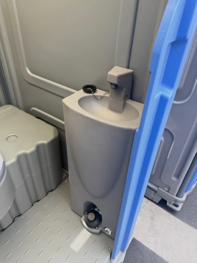 Portable restroom interior with a toilet and built-in sink