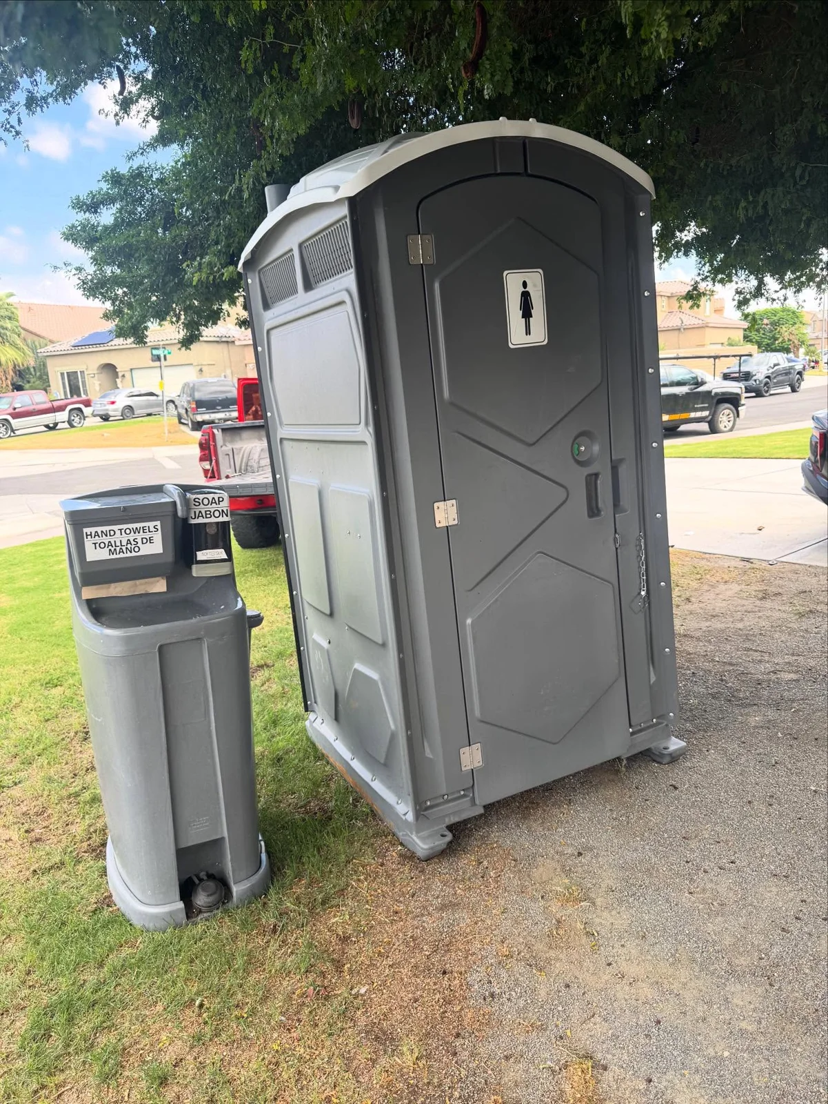 A freestanding handwashing station next to a portable restroom