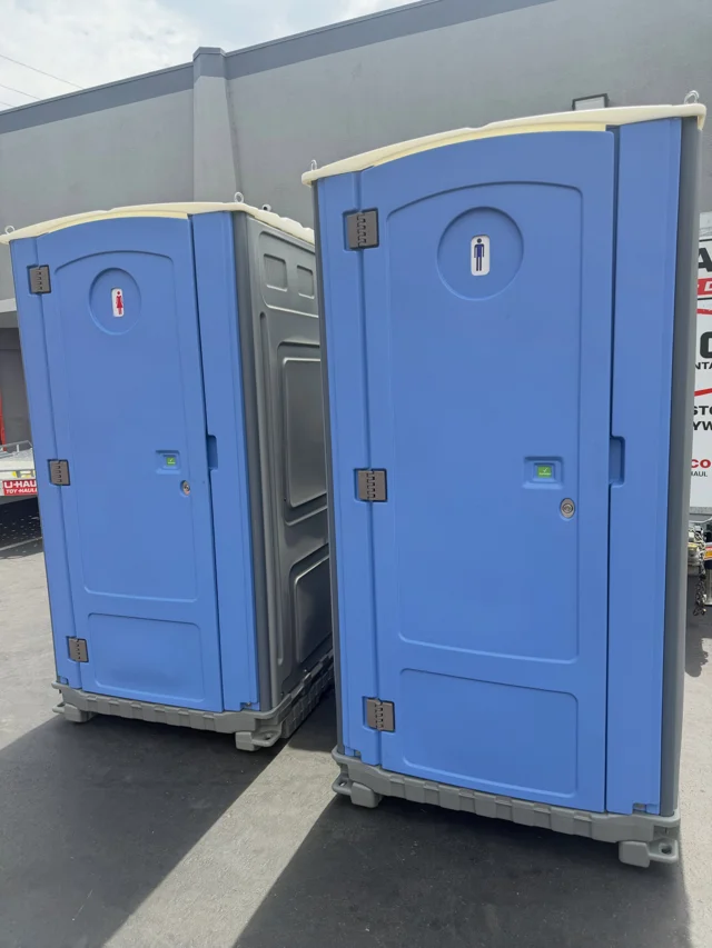 Two blue portable restroom units outdoors